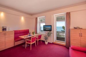 Strandhotel zur Promenade في بينز: غرفة بها أريكة حمراء وطاولة ونافذة