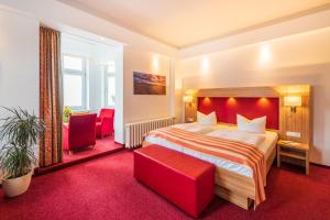 a hotel room with a bed and two red chairs at Strandhotel zur Promenade in Binz