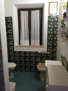 uma casa de banho com um WC, um lavatório e uma janela em Salina Holiday Home em Calasetta