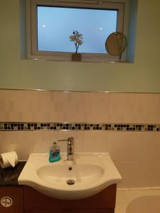 a white sink in a bathroom with a window at Moorland House in Syston