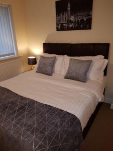 un grande letto con lenzuola bianche e cuscini grigi di Moorland House a Syston