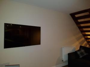 una TV a schermo piatto appesa a un muro bianco di Moorland House a Syston