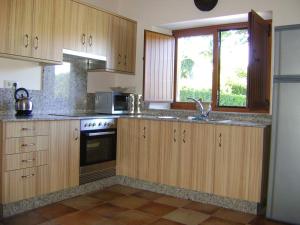 cocina con armarios de madera, fregadero y ventana en Stone Cottage FISTERRA en Curtis