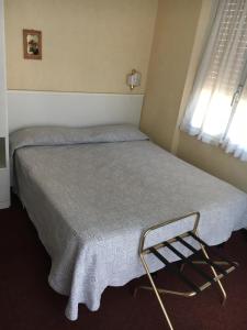 a small bedroom with a bed with a blanket and a window at Hotel Acqua Marina in Albissola Marina