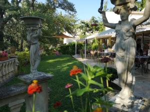 une statue d'une femme tenant une boulette dans un jardin dans l'établissement Au Bien Etre piscine, à Villecroze