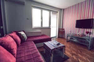 un soggiorno con un divano rosso e una TV di Square Vanilla Apartments a Skopje