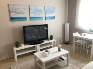 salon z telewizorem z płaskim ekranem i stołami w obiekcie Apartamento DELUXE Benalmádena w mieście Benalmádena
