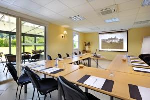 una sala de conferencias con mesas, sillas y ventanas en Brit Hotel Châteaudun, en Châteaudun