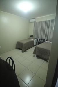 1 Schlafzimmer mit 2 Betten und Fliesenboden in der Unterkunft Mosaico Hotel in Dianópolis
