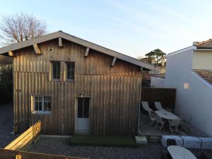 een houten gebouw met een patio en een tafel bij La cabane 26 D in Andernos-les-Bains