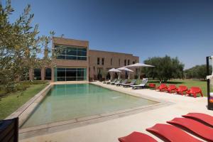 a swimming pool with chairs and a building at Villa Loanaelle in Marrakesh