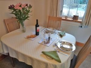 una mesa con una botella de vino y un jarrón de flores en Bridge of Bennie Cottage, en Banchory