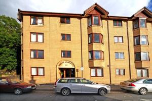 a large brick building with cars parked in front of it at 3 Albany Apartments - Oban in Oban