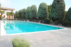 een groot zwembad met bomen op de achtergrond bij My Garda Holiday Home Peschiera 1 in Peschiera del Garda