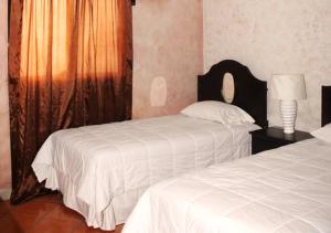 a bedroom with two beds and a lamp and a window at Apart Hotel K-Lisma in San Pedro Sula