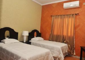 a bedroom with two beds with white sheets and a window at Apart Hotel K-Lisma in San Pedro Sula