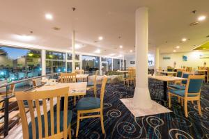 un restaurante con mesas y sillas de madera y ventanas en Copthorne Hotel & Resort Bay Of Islands en Paihia