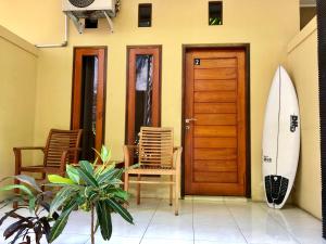 a room with a wooden door and a surfboard at Guest house KupuKupu39 in Kuta