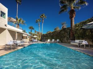 a swimming pool with chairs and palm trees at Movie Colony Hotel - Adults Only in Palm Springs