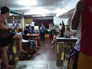 a group of people in a room with people sitting at tables at Jorge Transient House in Coron