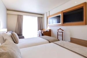 um quarto de hotel com duas camas e uma televisão de ecrã plano em Hotel Comfort Inn Ponta Delgada em Ponta Delgada
