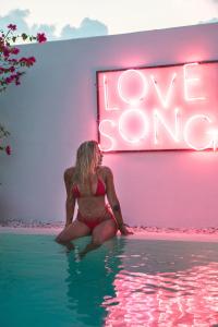 a woman in a bikini sitting in the water in front of a neon sign at Love Song Boutique Hotel in Canggu