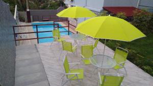 un patio con mesas, sillas y sombrillas amarillas en Casal.20 Studios Flats, en Cabo de Santo Agostinho