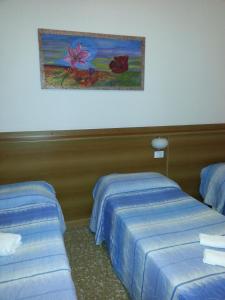 2 letti in una camera d'albergo con un dipinto sul muro di Hotel Lombardia a Seveso