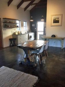 a kitchen with a wooden table and chairs in a room at Stylish Country Cottage, Solar panelled in Knysna in Knysna