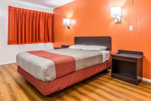 a bedroom with a bed with an orange wall at Motel 6-Tremonton, UT in Tremonton