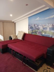a red couch in a room with a large mural at Lily's Apartment in Yerevan