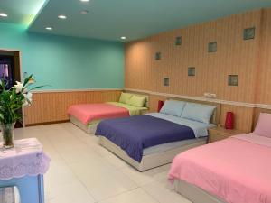 小琉球的住宿－苗甫民宿 ，粉红色和紫色的客房内的三张床