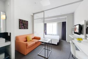 a living room filled with furniture and a large window at Citadines Shinjuku Tokyo in Tokyo