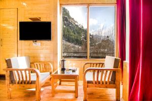 a living room with two chairs and a table and a window at FabExpress Shami Inn Naggar Road in Manāli