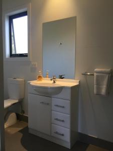 a bathroom with a sink, toilet and mirror at Kilcunda Ocean View Motel in Kilcunda