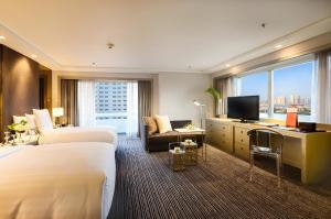 マニラにあるMidas Hotel and Casinoのベッド2台とテレビが備わるホテルルームです。