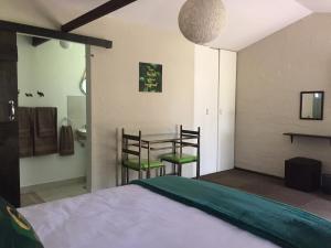 1 dormitorio con 1 cama, mesa y sillas en TreeTopia Guesthouse, en Benoni