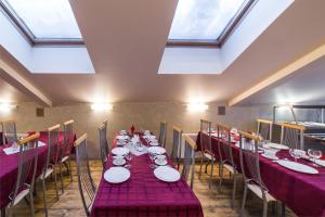 uma sala de jantar com mesas e cadeiras vermelhas e janelas em Hotel House of the Hunter em Toksovo