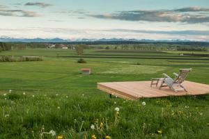 two chairs sitting on a wooden deck in a field at Hotel Alpenhof in Bad Wörishofen