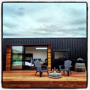 two chairs and a table on a wooden deck at Romantic Vineyard getaway in Waipara