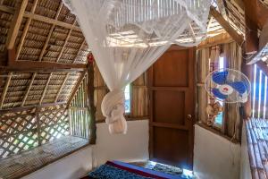 a room with a window with a curtain and a fan at Efrena Agro Tourism Beach in El Nido