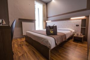 una camera d'albergo con un letto e una borsa sopra di Hotel Bigio a San Pellegrino Terme