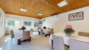 un restaurante con mesas blancas, sillas y flores en las mesas en Idan Lodge in the Arava, en Paran