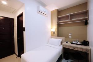 um quarto de hotel com uma cama, uma secretária e uma cama em Figtree Hotel em Iloilo City