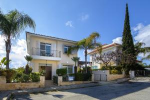 una casa blanca con palmeras delante en Villa Mesogeios 39 en Paralimni