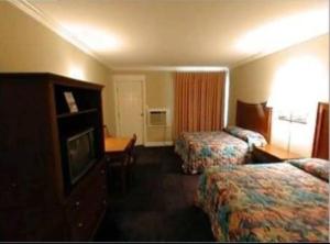 a hotel room with two beds and a television at Magnolia Beach Inn - Fairhope in Fairhope