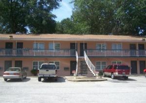 a large building with cars parked in a parking lot at Magnolia Beach Inn - Fairhope in Fairhope