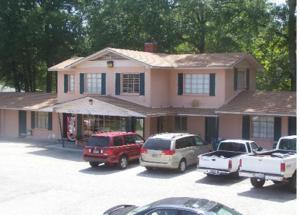 a pink house with cars parked in a parking lot at Magnolia Beach Inn - Fairhope in Fairhope