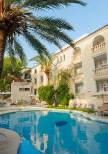 a swimming pool in front of a building with palm trees at APARTAMENTO EL ROJO in Can Picafort