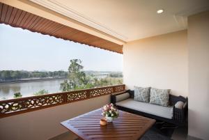 een balkon met een tafel en uitzicht op een rivier bij The Imperial River House Resort, Chiang Rai in Chiang Rai